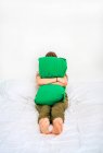 Full length of unrecognizable unhappy female embracing green pillow while sitting alone on bed at home — Stock Photo