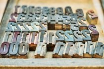 Alto ângulo de coleta de números de impressão de letras metálicas grungy colocados na bandeja na oficina — Fotografia de Stock