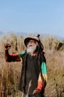 Веселое старое этническое растафари с дредами с закрытыми глазами и кулаками, празднующее победу на сухом лугу в природе — стоковое фото