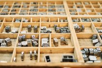 Набір металевих буквених літер, розміщених у дерев'яній коробці в типографії — стокове фото