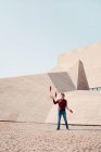 Полная длина мужского исполнительского трюка с жонглированием клубами, стоя напротив современного каменного здания с необычной геометрической архитектурой — стоковое фото