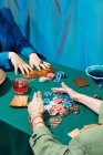 Ritaglia amiche irriconoscibili sedute al tavolo verde con carte e fiches mentre giochi d'azzardo — Foto stock