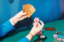 Ritaglia femmina irriconoscibile con carte e fiches giocando a poker mentre seduto al tavolo verde — Foto stock
