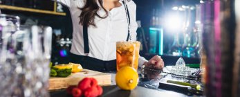 Cultivé femme barman méconnaissable dans une tenue élégante liquide de bouteille en verre tout en préparant un cocktail debout au comptoir dans le bar moderne — Photo de stock