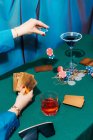 Ritaglia femmina irriconoscibile con carte e fiches giocando a poker mentre seduto al tavolo verde — Foto stock