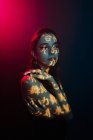 Модная молодая женская модель со светлой проекцией в виде восточных иероглифов, смотрящая в темную студию с красной подсветкой — стоковое фото