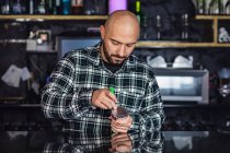 Mann bereitet traditionelle Wasserpfeife mit Folie in Nachtclub zu — Stockfoto