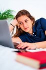 Freelancer jovem positivo em roupas casuais deitado na cama e digitando no laptop enquanto trabalhava em projeto remoto em casa — Fotografia de Stock