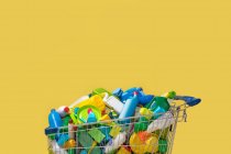 Корзина из разноцветных пластиковых пакетов на желтом фоне — стоковое фото