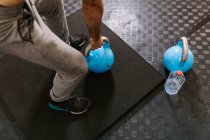 Cropped unrecognizable athletic male doing exercises with heavy kettlebell during active training in sports center — Stock Photo