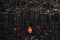 Jeune touriste en lunettes posant près de haut mur de pierre noire — Photo de stock