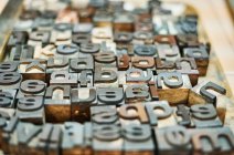 Conjunto de letras y números metálicos de tipografía en forma de tipografía colocados en caja de madera - foto de stock