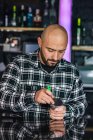 Mann bereitet traditionelle Wasserpfeife mit Folie in Nachtclub zu — Stockfoto
