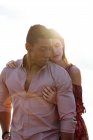Amare donna abbracciando uomo nero da dietro mentre trascorreva la giornata estiva insieme sulla riva del mare — Foto stock