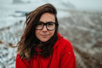 Молодий щасливий турист в окулярах з пірсингом дивиться на камеру між покинутою землею в снігу — стокове фото