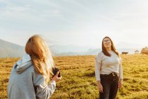 Vue de dos femelle prendre des photos de petite amie avec des lunettes de soleil et passer du temps ensemble dans les montagnes — Photo de stock