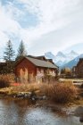 Picturesque autumnal landscape with wooden houses located near river against snowy mountains in town of Canmore near Banff National Park of Canada — Stock Photo