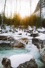 Rapid river flowing near stony coast covered with snow and coniferous trees at sunset in Marble Canyon, British Columbia — Stock Photo