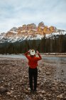 Vue arrière d'une voyageuse anonyme admirant le mont Castle enneigé et les conifères alors qu'elle se tenait sur la côte d'une rivière dans le parc national Banff — Photo de stock
