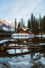 Long bridge crossing Emerald Lake near wooden cottage located near coniferous forest and snowy mountain on winter day in British Columbia, Canadá — Fotografia de Stock