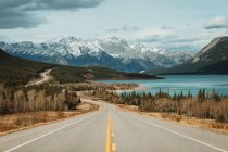 David Thompson Highway going near Abraham Lake and snowy mountains on cloudy day in Banff National Park — Stock Photo