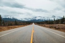 David Thompson Highway gegen verschneite Berge am bewölkten Tag im Banff National Park — Stockfoto