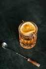 Composición de whisky helado frío adornado con rodaja de limón y colocado en la mesa negra - foto de stock