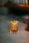 Composizione di whisky freddo ghiacciato guarnito con fetta di limone e posto sul tavolo di cemento — Foto stock