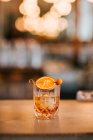 Composizione di whisky freddo ghiacciato guarnito con fetta di limone e posto sul tavolo di cemento durante la notte in un bar — Foto stock