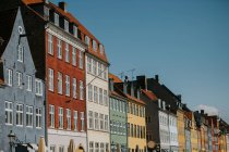 From below of bright brick and stone apartment buildings against cloudless blue sky in Copenhagen — Stock Photo