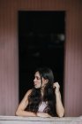 Спокійна мрійлива жінка-підліток з довгим темним волоссям, що стоїть, дивлячись на дощату стіну — стокове фото