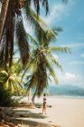 Vista laterale di donna irriconoscibile in costume da bagno godendo di vacanze estive sulla pittoresca riva del mare con palme tropicali e spiaggia sabbiosa nella città di Uvita in Costa Rica — Foto stock