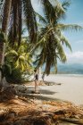 Vista lateral de una mujer irreconocible en traje de baño disfrutando de vacaciones de verano en la pintoresca orilla del mar con palmeras tropicales y playa de arena en la ciudad de Uvita en Costa Rica - foto de stock