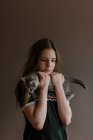 Soñadora adolescente reflexiva sosteniendo lindo gato esponjoso sobre fondo marrón en el estudio - foto de stock
