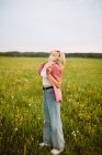 Happy young female standing in meadow in summer — Stock Photo