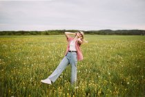 Happy young female standing in meadow in summer — Stock Photo