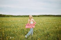 Вид збоку анонімної жінки, що йде квітучим літнім полем і насолоджується свободою — стокове фото