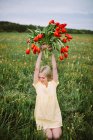 Sorridente femmina affascinante con bouquet di fiori di tulipano rosso seduto in prato verde in estate — Foto stock