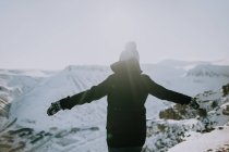 Rückenansicht einer anonymen Reisenden, die mit ausgestreckten Armen im Hochland im Winter in Spitzbergen die Freiheit genießt — Stockfoto