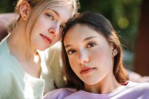 Zarte Teenie-Schwestern blicken an einem sonnigen Sommertag im grünen Garten in die Kamera — Stockfoto