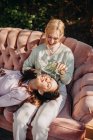Sœurs adolescentes tranquilles se reposant ensemble sur le canapé tout en se refroidissant sur la terrasse en été par une journée ensoleillée — Photo de stock