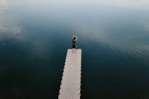 Зверху віддалений вид чоловіка, що стоїть на краю набережної біля спокійного озера — стокове фото