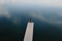 Dall'alto vista remota di maschio in piedi sul bordo del molo vicino al lago calmo — Foto stock