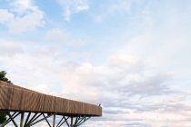 Vue à distance de la personne debout sur le point de vue en bois sur fond de ciel nuageux au coucher du soleil incroyable — Photo de stock