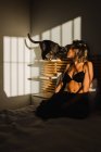Shirtless mulher abraçando bonito gato na prateleira do quarto perto da cama com luz entrar no quarto — Fotografia de Stock