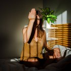 Tiro de uma mulher bonita sensual jogando entre luz e sombra cobrindo o olho com a mão — Fotografia de Stock