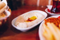 Piatto con gustoso hummus tradizionale posto in tavola vicino a piatti in ristorante in Turchia — Foto stock