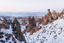 Formazioni rocciose grezze coperte di neve bianca contro il cielo serale senza nuvole in Cappadocia, Turchia — Foto stock