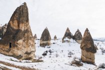 Desde arriba camino de tierra contra la colina nevada con famosos pilares con afilados picos en forma de lanza en el parque nacional en Turquía - foto de stock