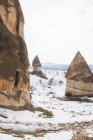 Desde arriba camino de tierra contra la colina nevada con famosos pilares con afilados picos en forma de lanza en el parque nacional en Turquía - foto de stock